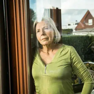 Eine Seniorin blickt aus dem Fenster