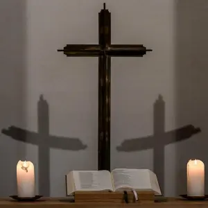Brennende Kerzen und Kreuz
