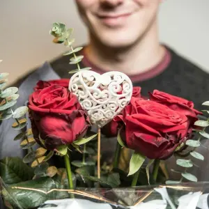 Ein grinsender Mann hält Rosen in der Hand