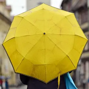 Eine Passantin mit gelbem Regenschirm