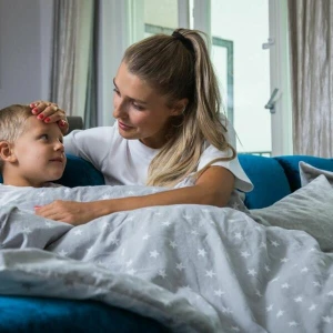 Eine Mutter fasst ihrem Sohn prüfend an die Stirn