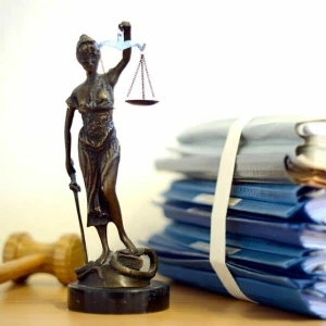 Eine Statuette der Justitia vor einem Aktenstapel