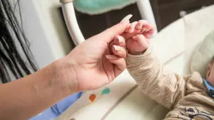 Ein Erwachsener häält die Hand eines Kleinkindes