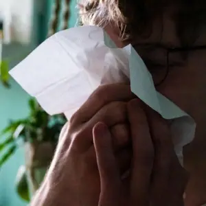 Ein Mann putzt sich mit einem Taschentuch die Nase