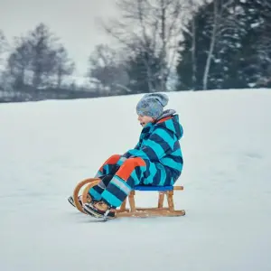 Ein Kind sitzt auf einem Holzschlitten