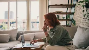 Eine Frau sitzt an einem Laptop auf einer Couch