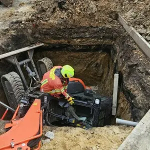 Bagger fällt in Baugrube