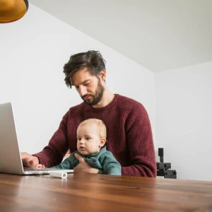 Mann mit Kleinkind im Homeoffice