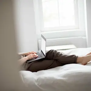 Eine Frau sitzt mit Laptop im Bett