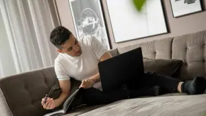 Ein Mann sitzt mit Laptop auf einem Sofa