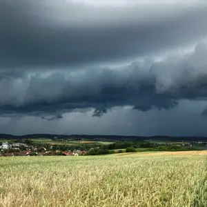 Eine Gewitterzelle mit dunklen Wolken baut sich am Himmel auf