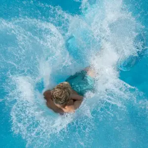 Ein Junge springt in einem Freibad ins Wasser