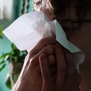 Ein Mann putzt sich mit einem Taschentuch die Nase