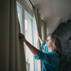 Eine Frau schliesst Vorhänge in einer Dachgeschosswohnung