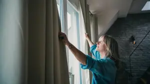 Eine Frau schliesst Vorhänge in einer Dachgeschosswohnung