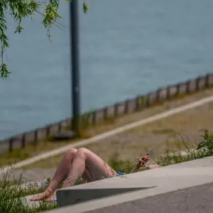 Eine Frau sonnt sich am Rheinufer.