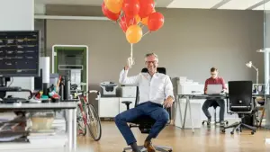Mann mit Luftballons im Büro