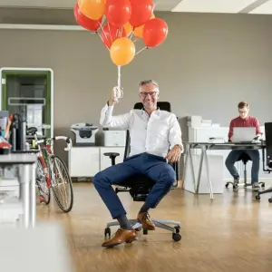 Mann mit Luftballons im Büro