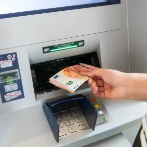 Eine Person holt Geld vom Automaten