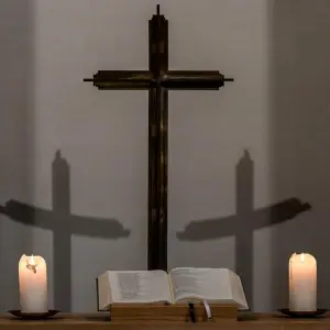 Brennende Kerzen und Kreuz