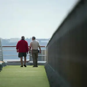 Ältere Passagiere auf dem Oberdeck eines Kreuzfahrtschiffs