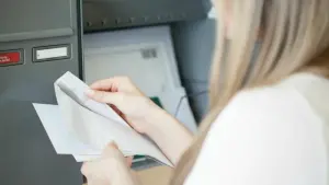 Person holt Post aus Briefkasten und liest Schreiben