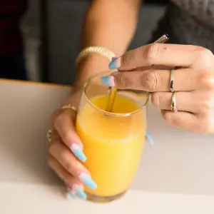 Eine Person greift nach einem Glas Orangensaft
