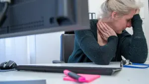 Eine Frau stützt ihren Kopf auf die Hand am Arbeitsplatz
