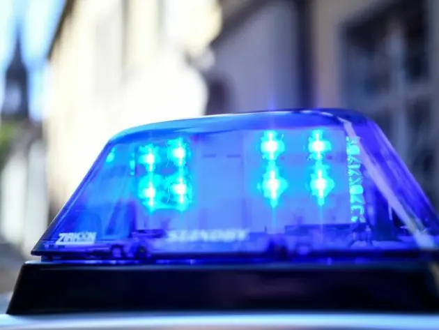 Ein Polizeiauto mit blinkendem Blaulicht steht vor einem Gebäude