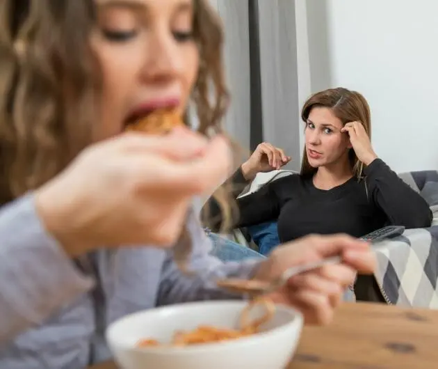 Zwei Frauen im Wohnzimmer, eine Frau isst.