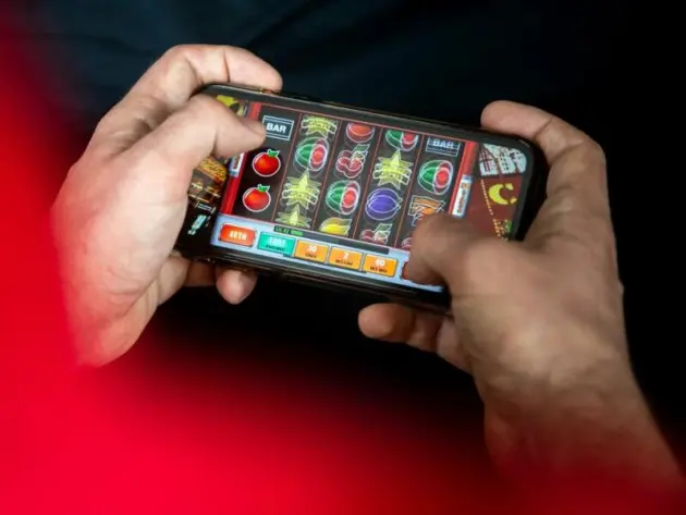 Ein Mann spielt am Smartphone ein Glücksspiel