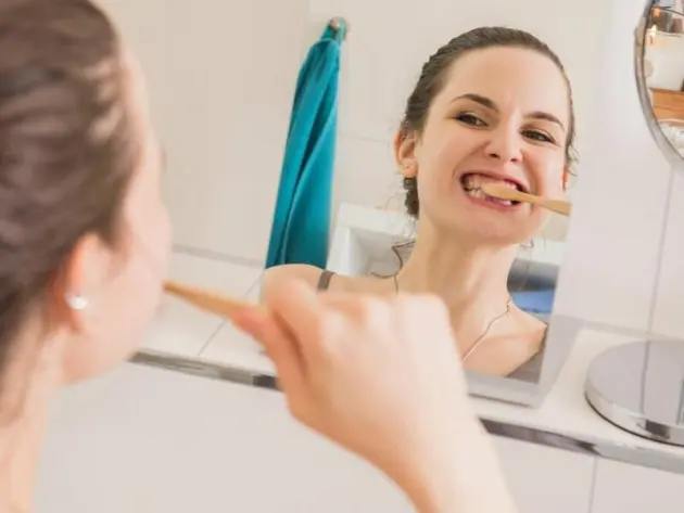 Frau putzt sich mit einer Bambus-Zahnbürste die Zähne