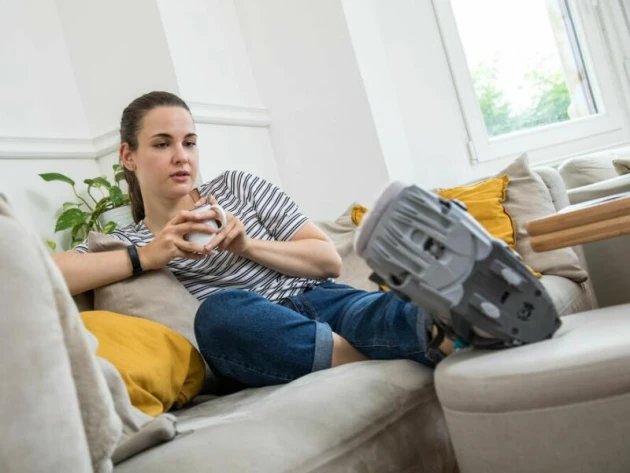 Eine Frau liegt mit einer Orthese auf dem Sofa