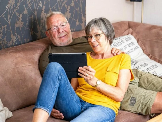 Ein Paar sitzt schaut auf ein Tablet