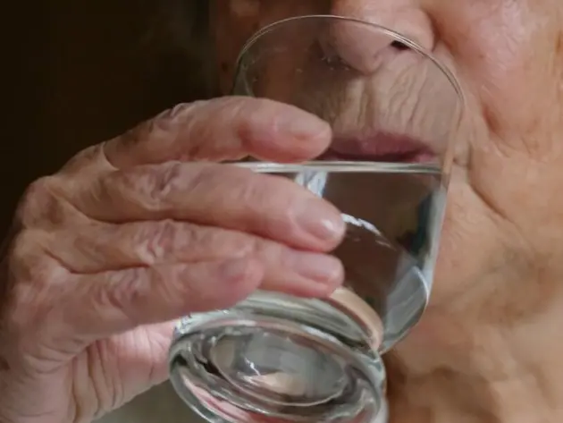 Eine Seniorin trinkt ein Glas Wasser