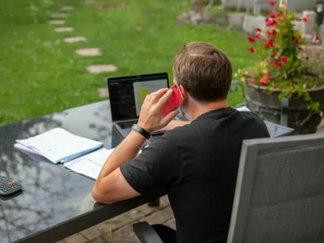 Ein Mann sitzt im Garten am Laptop