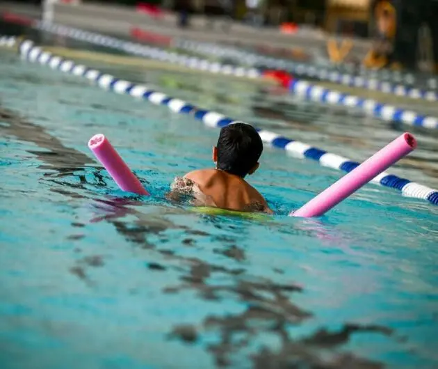 Kind mit Schwimmnudel im Sportbecken