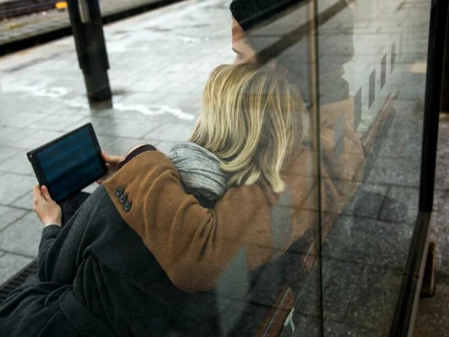 Ein Paar sieht auf ein Tablet am Bahnhof