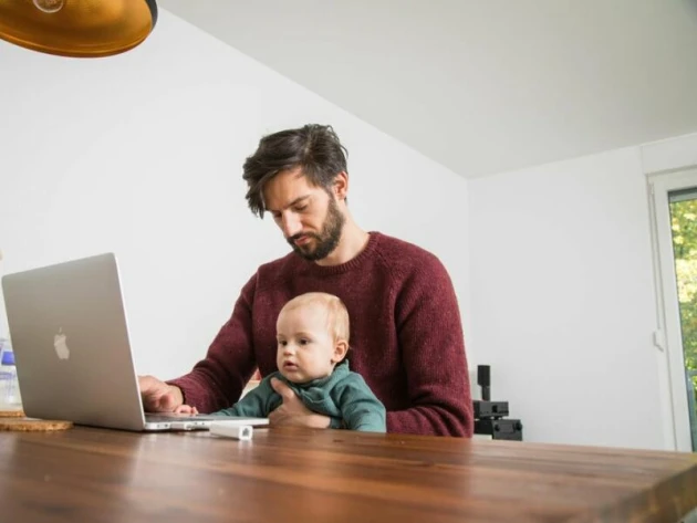 Mann mit Kleinkind im Homeoffice