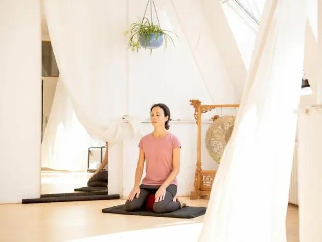Eine Frau meditiert in einer Yoga-Ecke